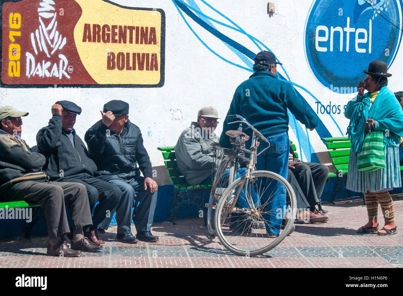 Älteren bolivianischen Männern zur freien Verfügung in Uyuni.  Werbung über ihren Köpfen bezieht sich auf den motor Rallye Dakar 2016. Stockfoto