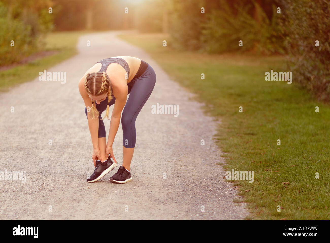 Junge Frau vor dem Training, Übungen Übungen, dehnen sie Muskeln auf einem Feldweg im Morgenlicht Stockfoto