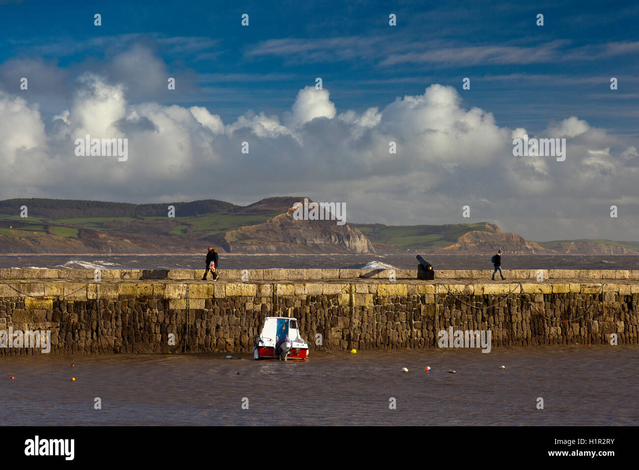 Spaziergänger genießen die Wintersonne am Hafen Wand in Lyme Regis, Dorset, England, UK Stockfoto