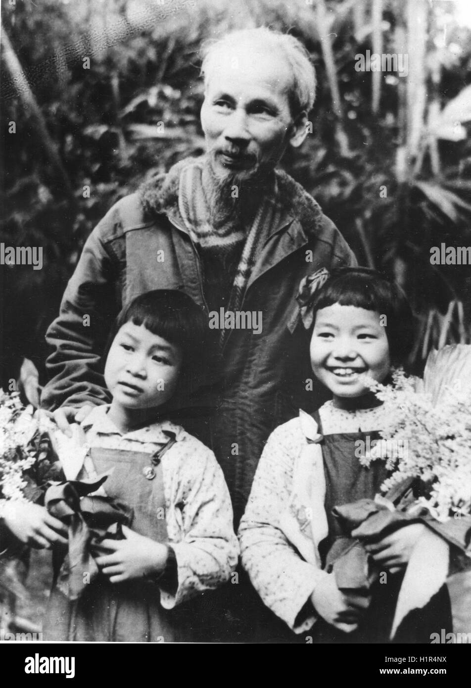 Präsident Ho Chi Minh mit zwei Kindern, die ihn mit Blumen am 2. Jahrestag der Gründung des Vietnams Lao-Gong-Partei (Partei des vietnamesischen Volkes arbeiten) vorgestellt. Stockfoto
