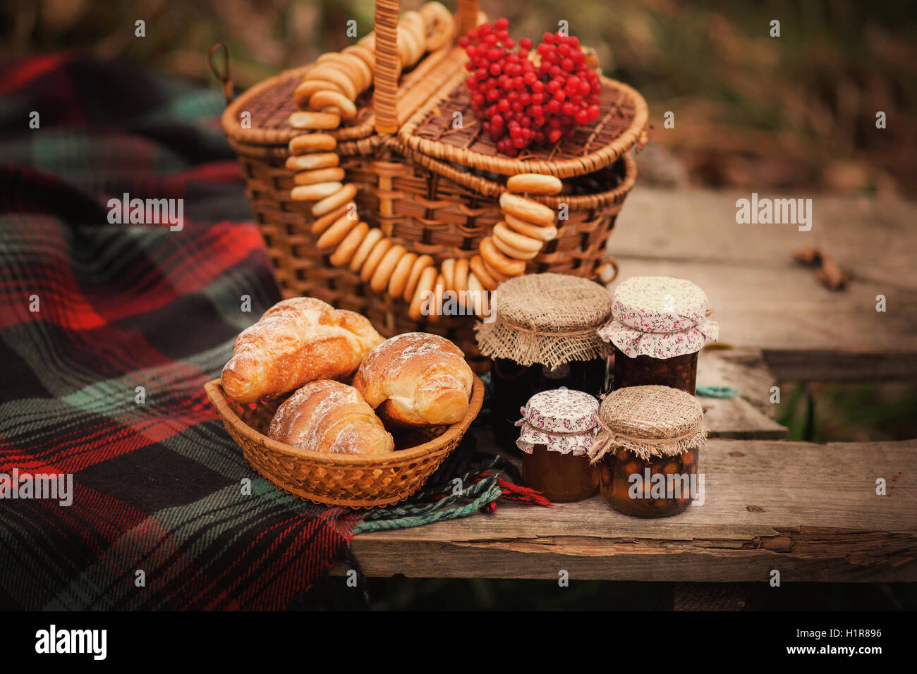 Land-Stillleben. Alten Holztisch mit Marmelade in Gläsern, Weidenkörbe und andere Symbole der Herbst im Garten. Stockfoto