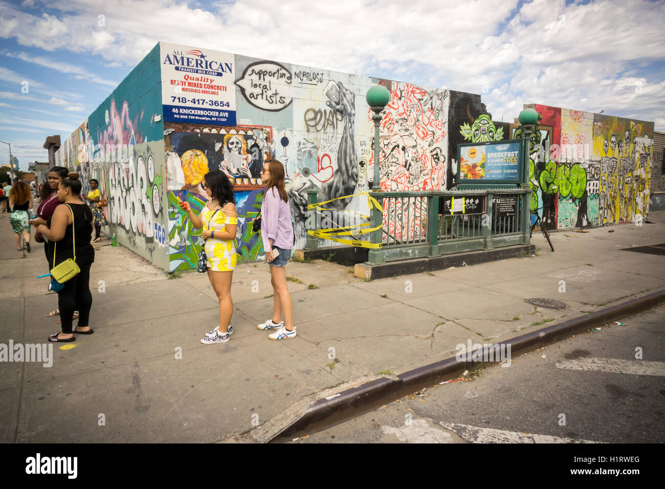 Besucher zu Fuß vorbei an Graffiti-Stil Wandmalereien im Stadtteil Bushwick, Brooklyn in New York auf Sonntag, 11. September 2016. Die Nachbarschaft hat Gentrifizierung der Wechsel von einer rauen und Wäschetrockner Mischung von Hispanic und von Industrie, eine Oase für Hipster, zwingt viele alteingesessene, wegen der steigenden mieten. (© Richard B. Levine) Stockfoto