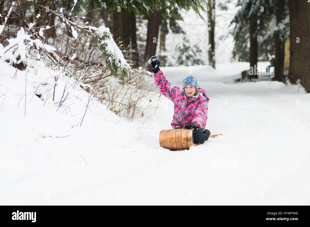 Mädchen einen Schnee bedeckten Hügel hinunter auf einen alten hölzernen Schlitten Rodeln Stockfoto