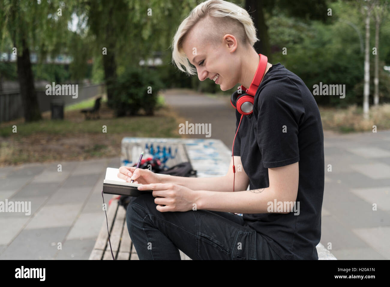 Lächelnde junge Frau, die Zeichnung auf Parkbank Stockfoto