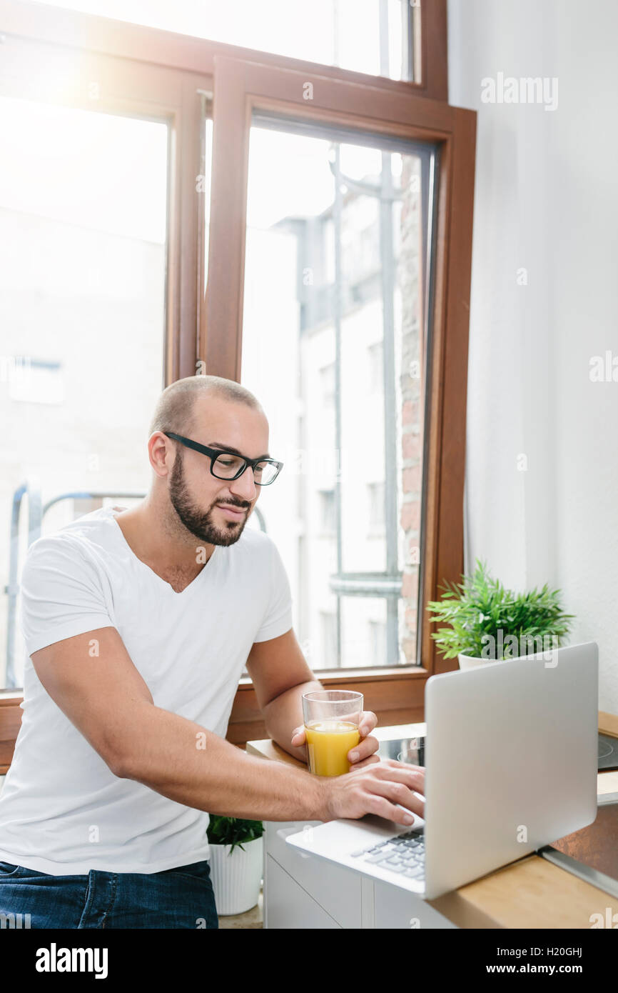 Homosexuell Mann Orangensaft zu trinken, beim Lesen von e-Mails Stockfoto