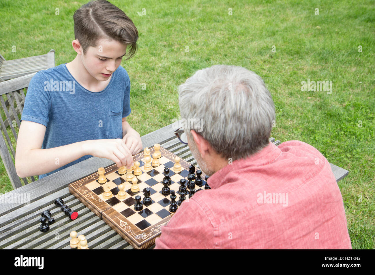 Vater und Sohn beim Schachspiel im Garten Stockfoto