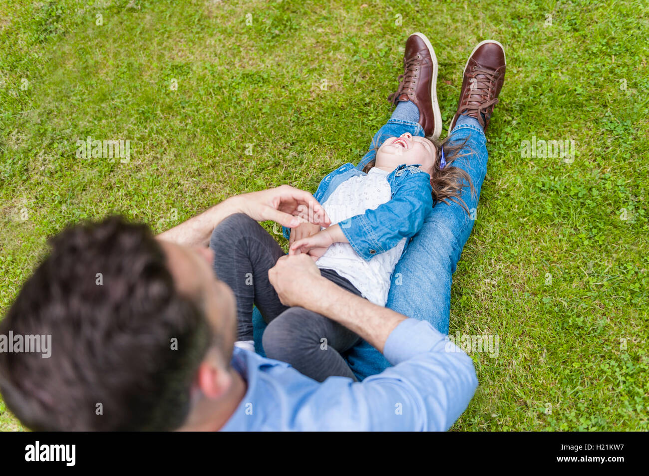 Vater kitzeln Tochter auf Wiese im park Stockfoto
