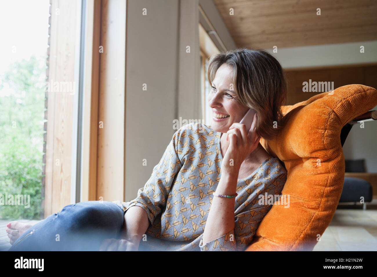 Lächelnde Frau zu Hause auf Handy Stockfoto