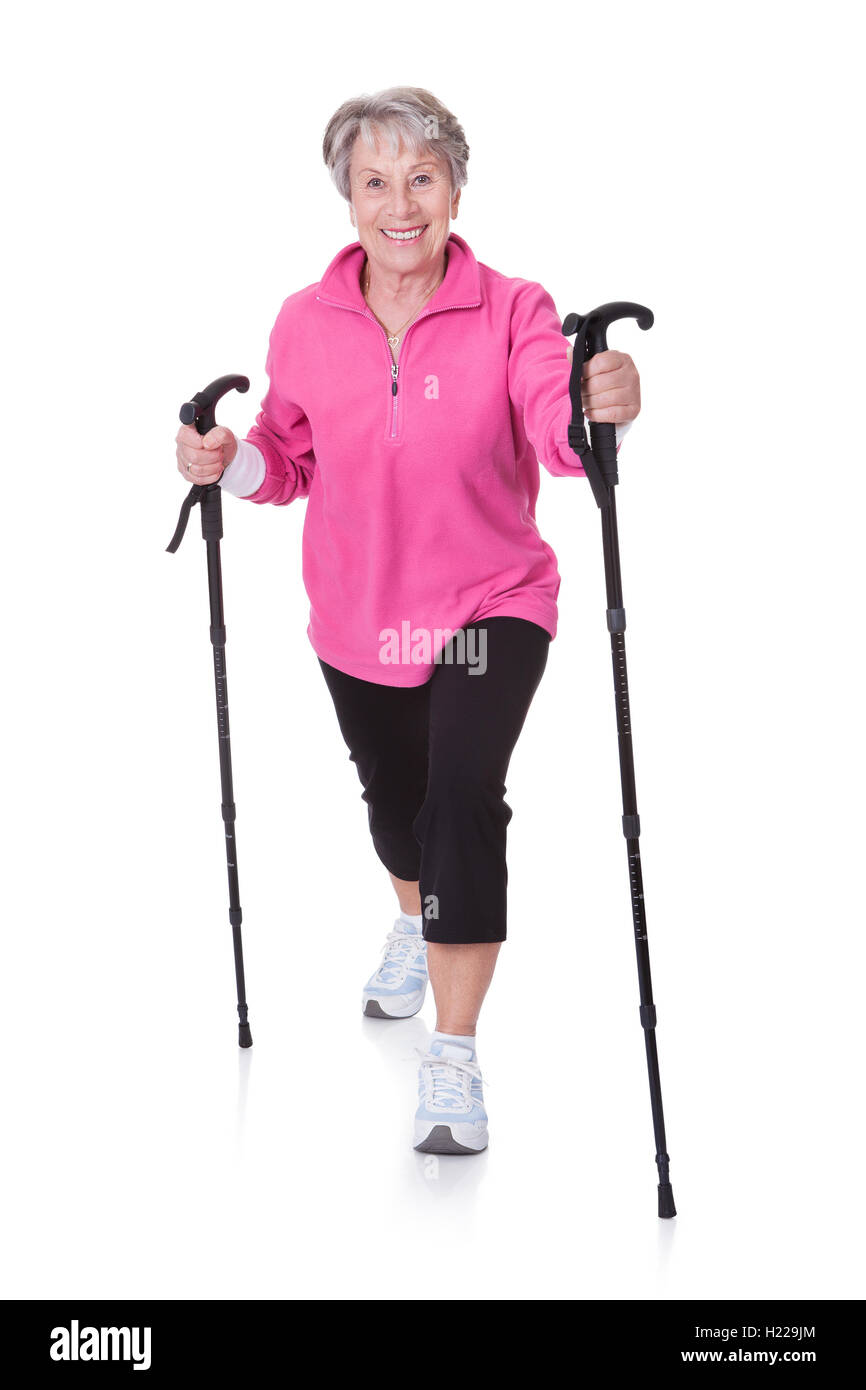 Senior Woman Walking mit Wanderstöcken Stockfoto