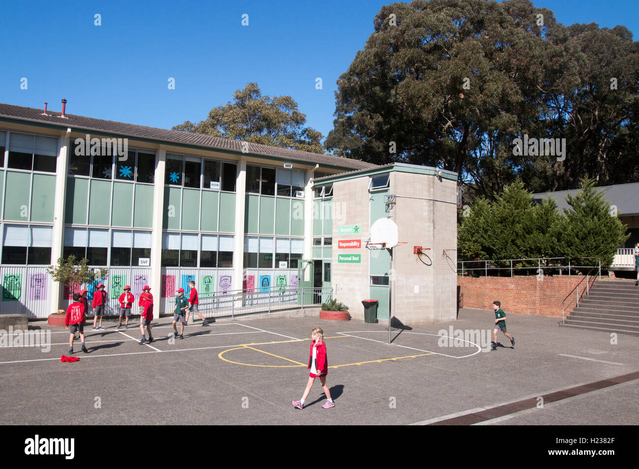 Australische Schulkinder spielen Sport auf dem Schulspielplatz in roter Schuluniform, blauer Himmel Wintertag, Sydney Australien Stockfoto