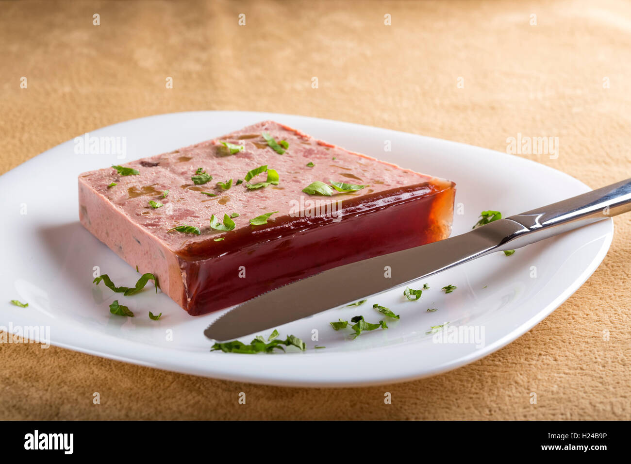 Leberpastete auf Platte aus Schwein und Reh Fleisch auf weißen Teller mit Küchenmesser Stockfoto