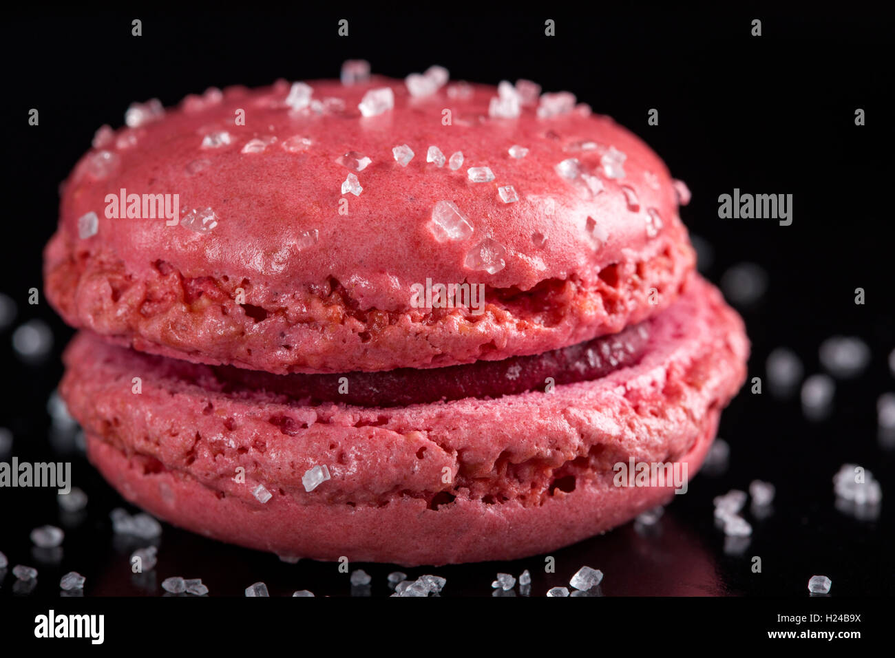 Nahaufnahme von einem rosa Makronen-Kuchen mit Zucker auf schwarzem Hintergrund Stockfoto