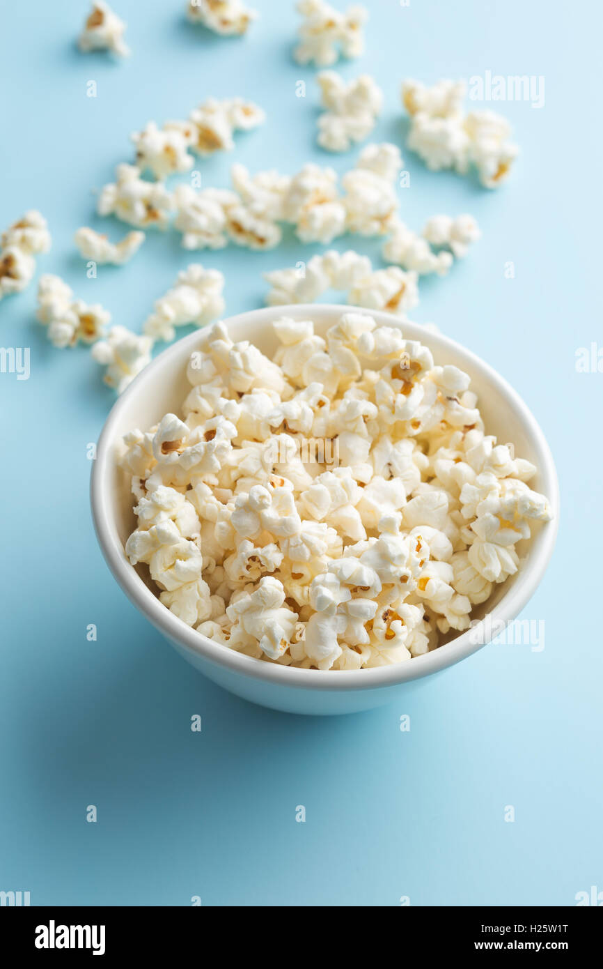 Popcorn in Schüssel auf blauem Hintergrund. Stockfoto