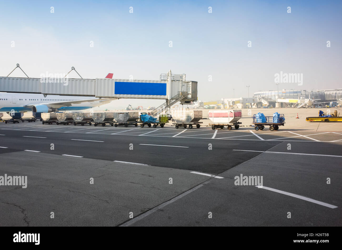 Gepäckverladung in europäischen Flughafen. Fracht Wagen auf dem Rollfeld Landebahn Stockfoto
