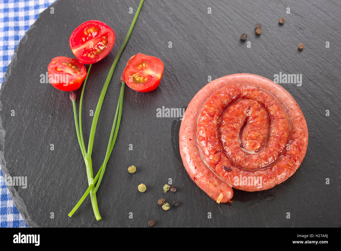 Gerollte Wurst auf einer schwarzen Platte. Stockfoto