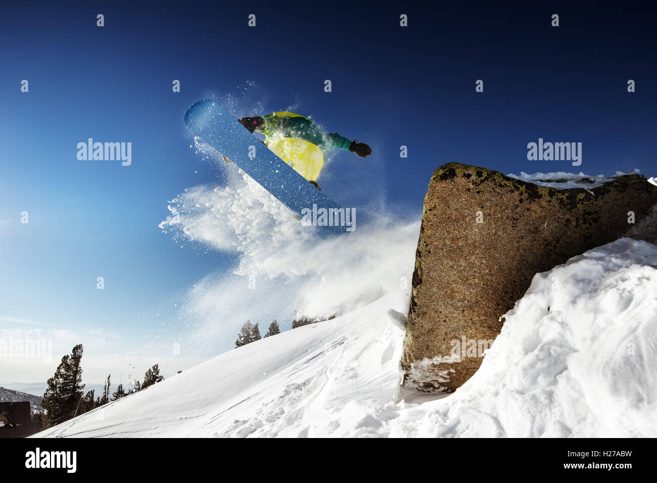 Snowboarder posiert auf blauen Himmel Hintergrund in Bergen Stockfoto