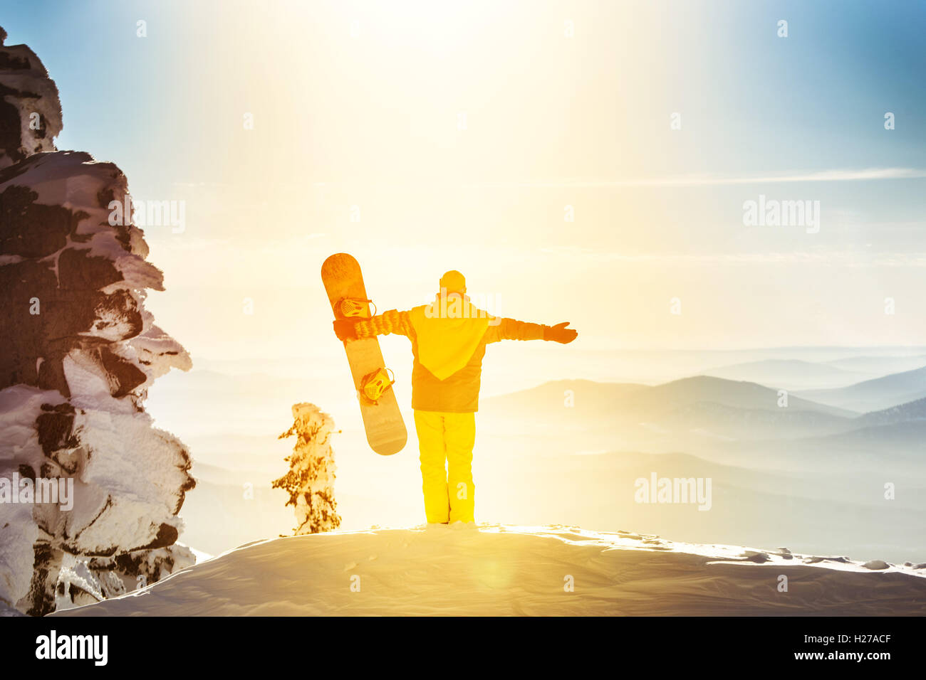 Snowboarder posiert auf blauen Himmel Hintergrund in Bergen Stockfoto