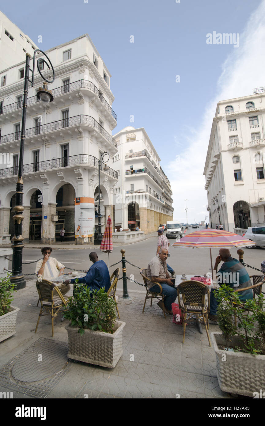 Französische Kolonialbauten und Menschen, die in einem Straßencafé in Algier Algeria.Buildings Cofeee werden renoviert. Stockfoto