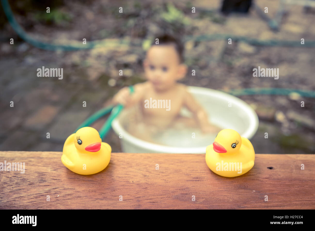 gelbe Ente auf Holzbrett mit unscharfen Baby Baden Hintergrund Stockfoto