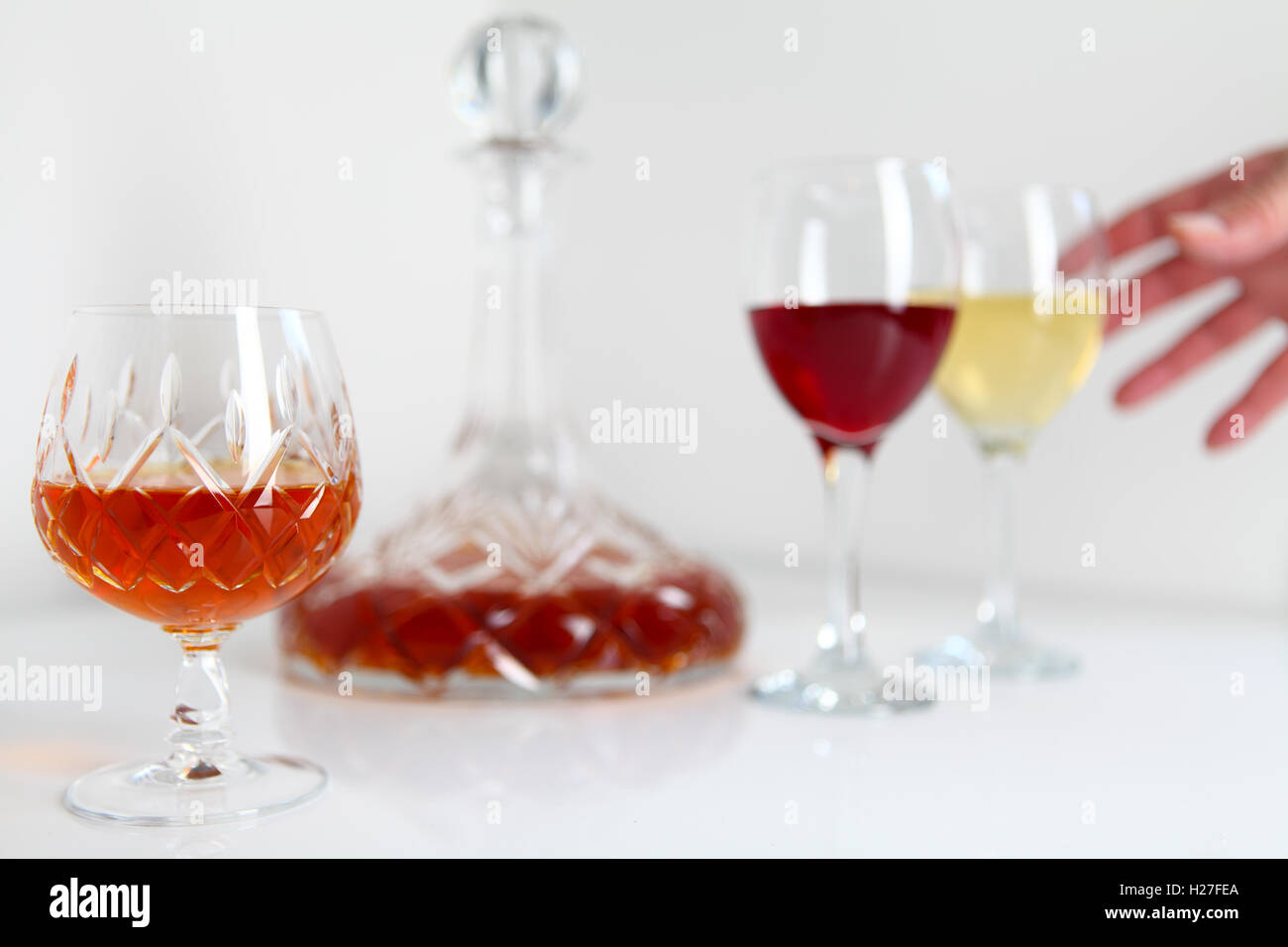 Nicht identifizierter Hand greift nach Weinbrand oder Cognac in geschliffenem Glas Becher mit Dekanter mit weiß- und Rotwein Stockfoto