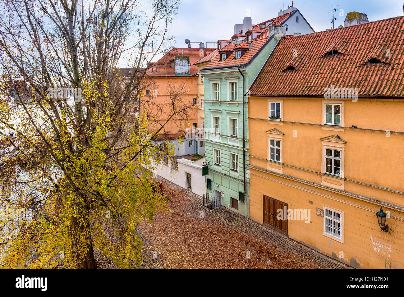 Alten Kopfsteinpflasterstraße zwischen Baum mit gelben Blättern und bunten Häuser in Prag, Tschechien. Stockfoto
