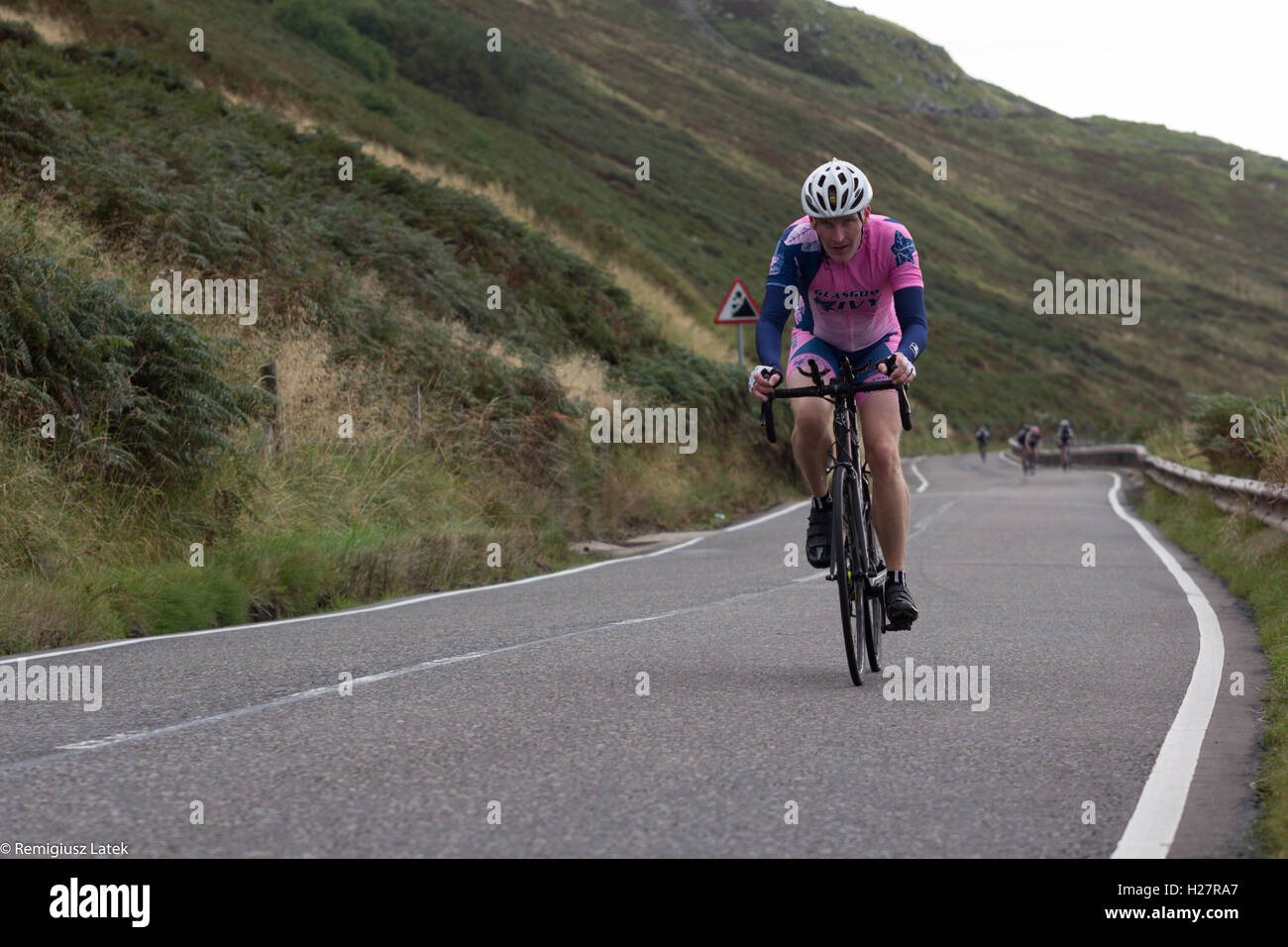 Beschleunigen professionell gekleidet Radfahrer auf dem Asphalt während des Wettbewerbs in Schottland Stockfoto