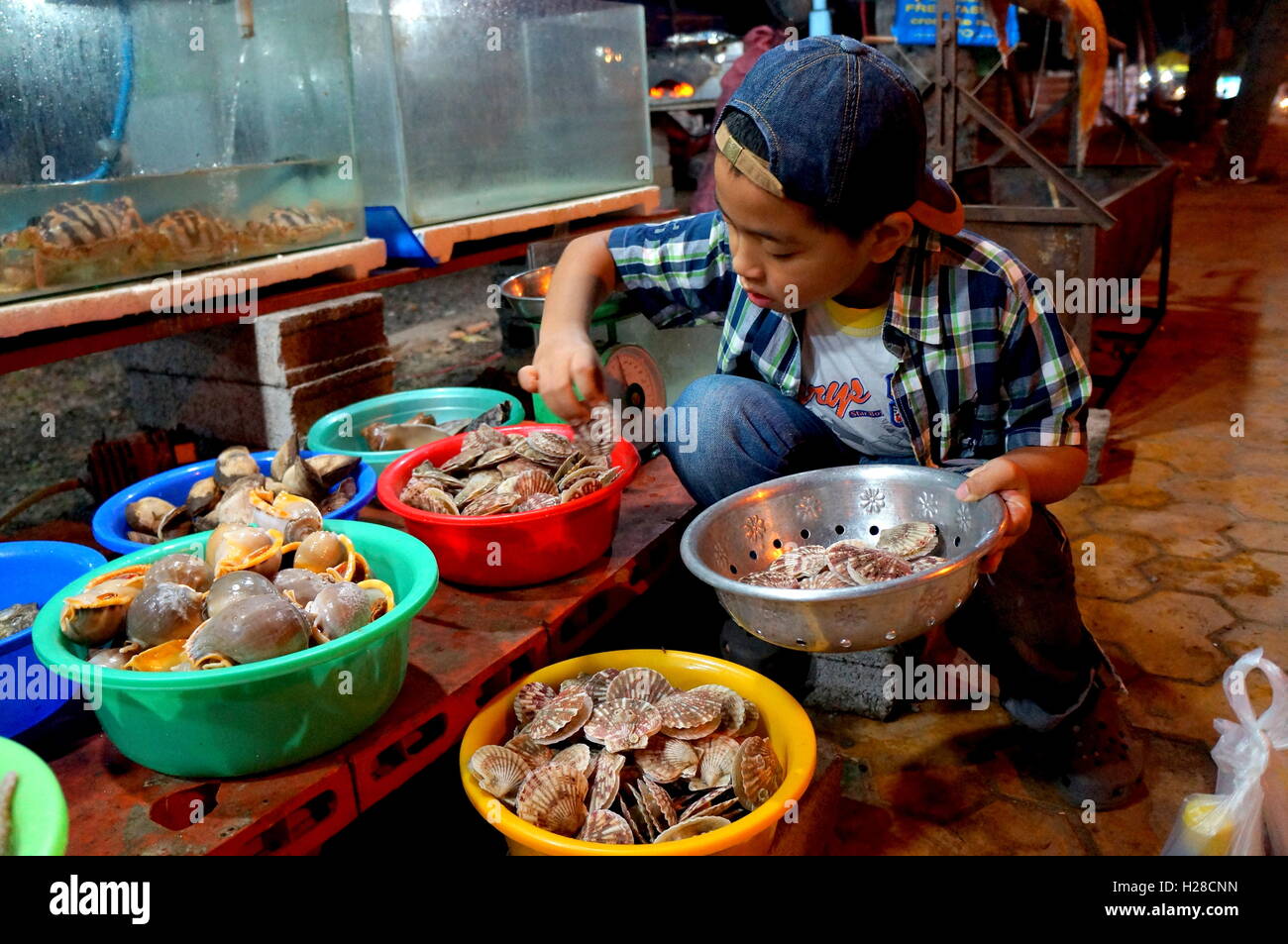 Saigon, Vietnam - 1. Februar 2016: Ein Kind ist Muscheln zum Essen in ein Speiselokal Anbieter in Vietnam auswählen Stockfoto