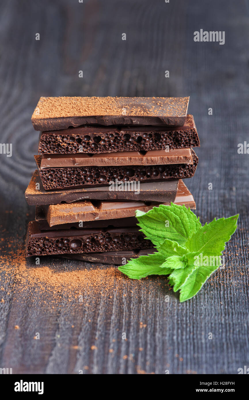 Verschiedenen Schokoladenstangen auf dem hölzernen Hintergrund mit Minze-Zweig Stockfoto
