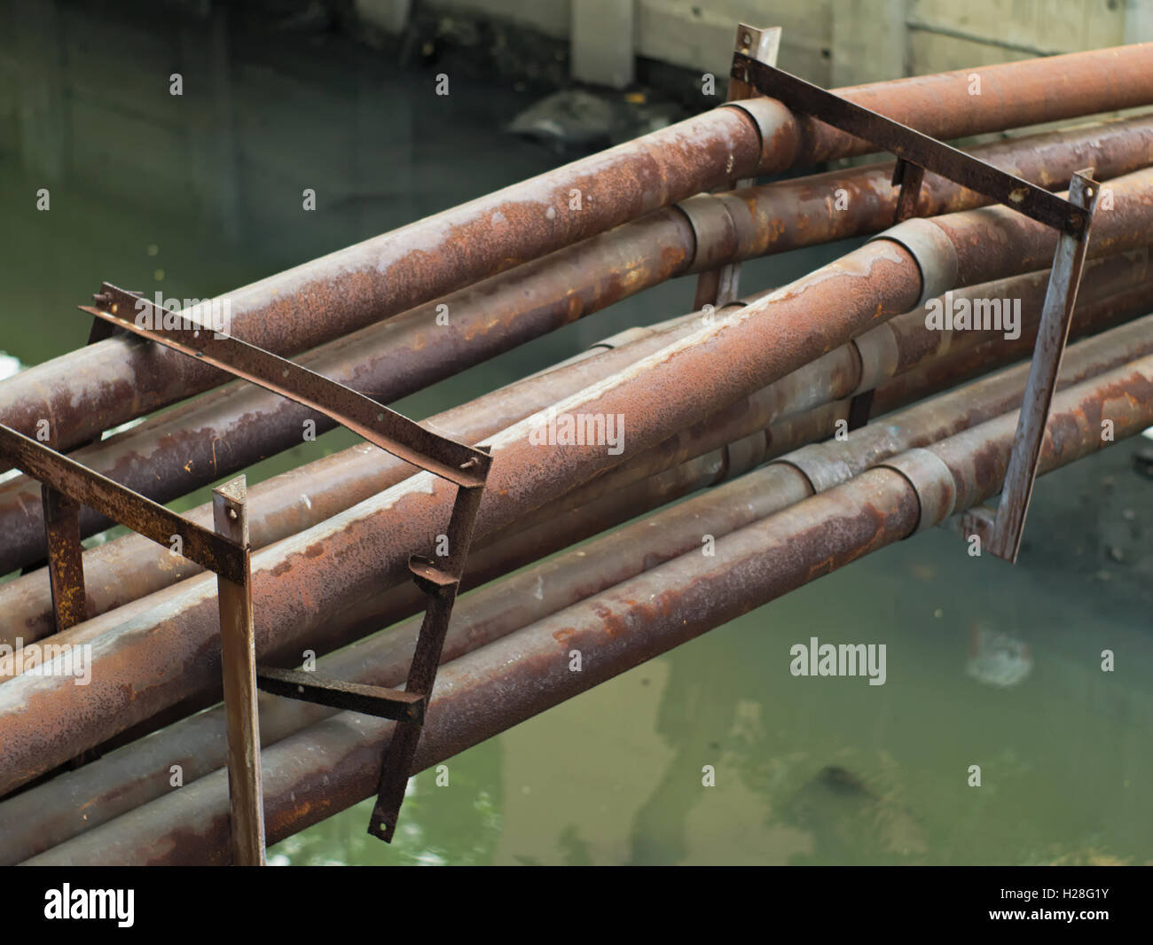 rostige Wasserleitungen über einen schmutzigen Kanal Stockfoto