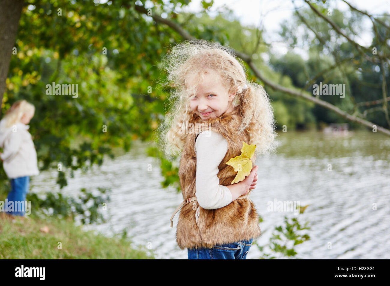 Mädchen versteckt Herbst Blatt als Überraschung Spiel und Spaß im Urlaub Stockfoto