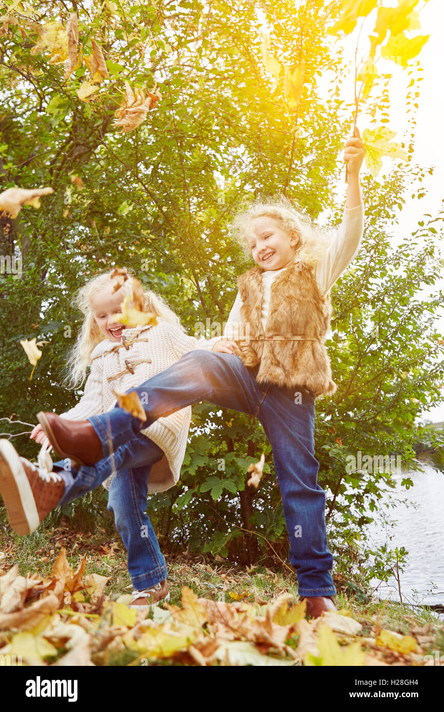 Zwei Kinder spielen und tanzen im Herbst mit Blättern Stockfoto