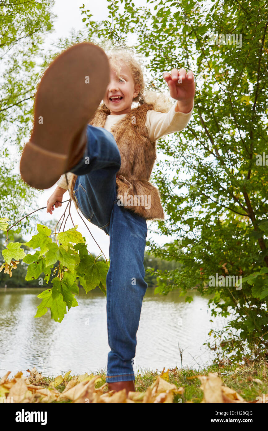 Kinder toben im Herbst in der Natur und Tritte die Blätter Stockfoto