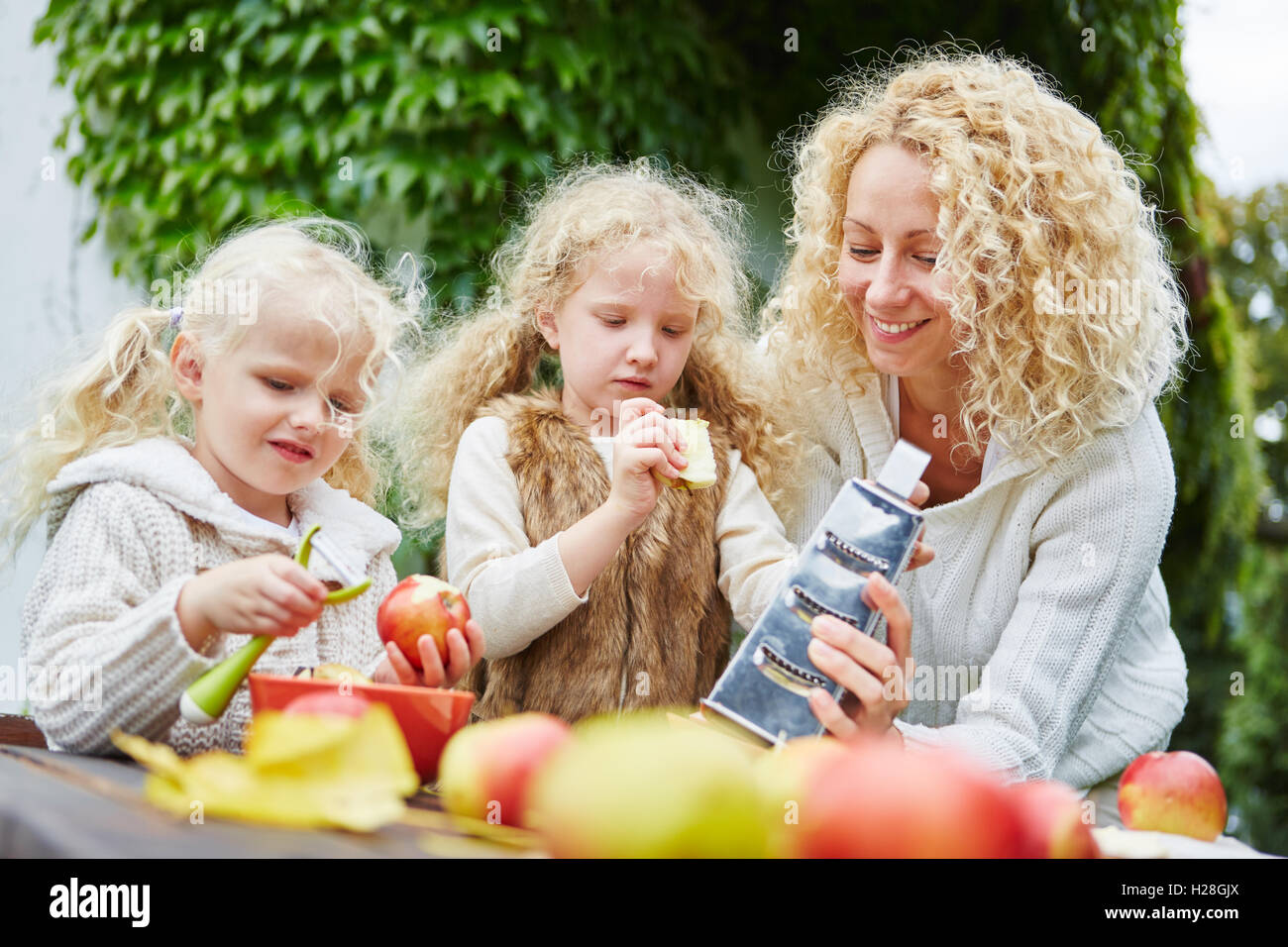 Familie mit Kindern peeling Äpfel als Teamarbeit im Garten Stockfoto