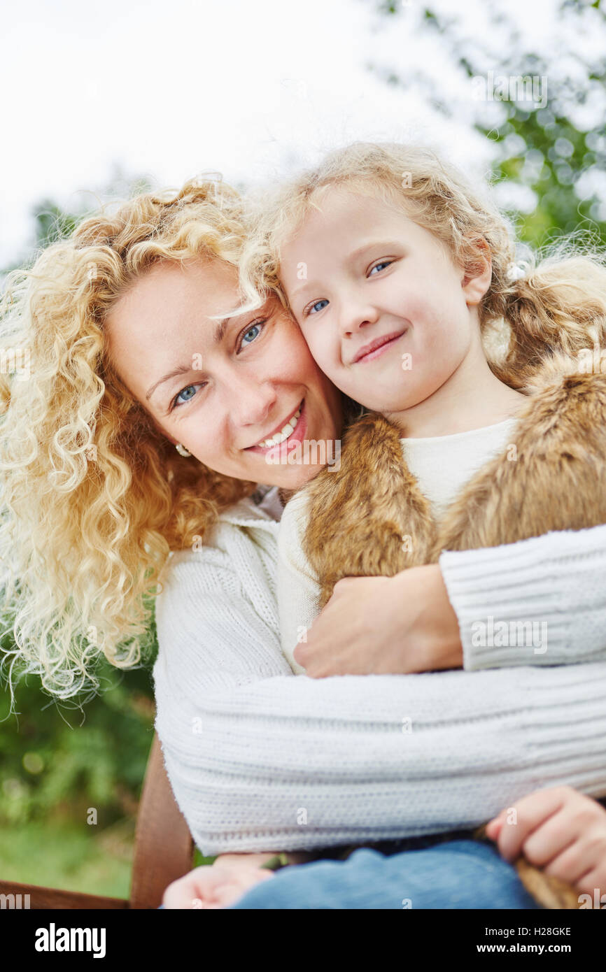Glückliche Mutter umarmt Tochter mit Liebe in Familienporträt Stockfoto