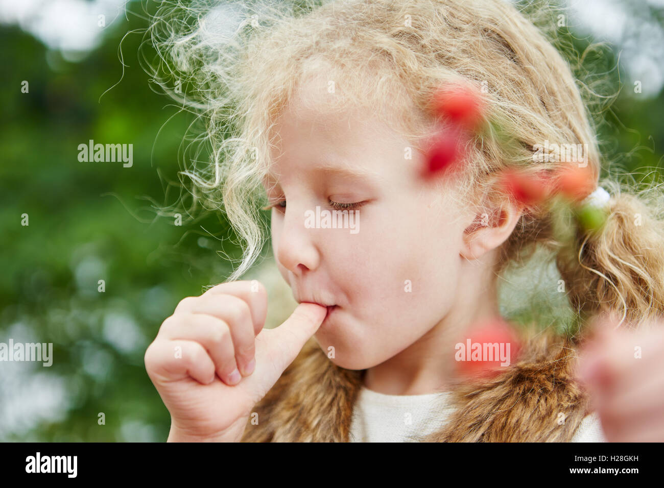Kleines Mädchen saugen ihre Daumen und Abholung Hagebutten im Herbst Stockfoto