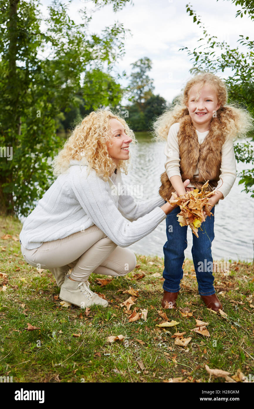 Mutter und Tochter sammeln Blätter im Garten im Herbst Stockfoto