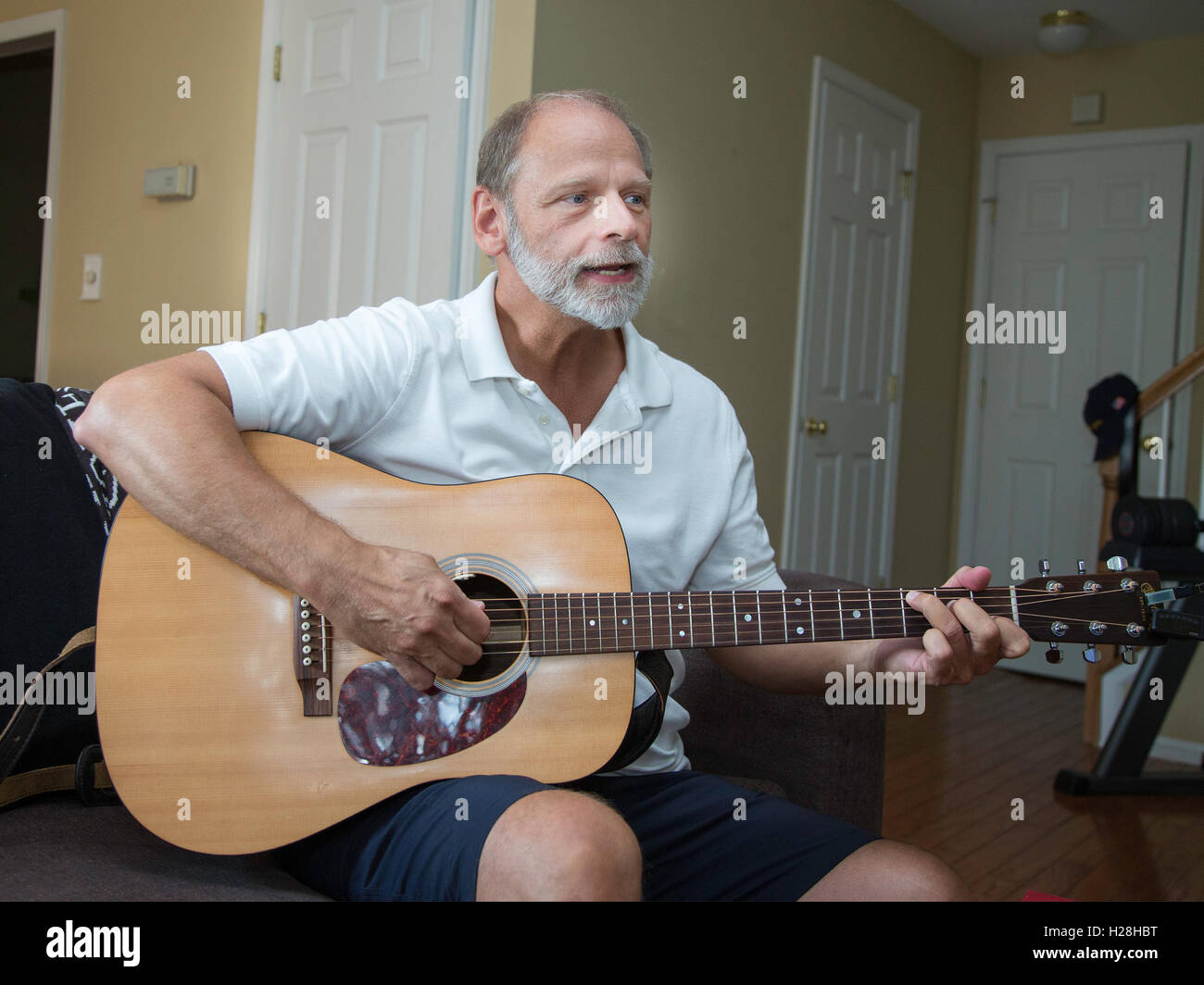 Mann spielt Gitarre in seiner Wohnung Stockfoto