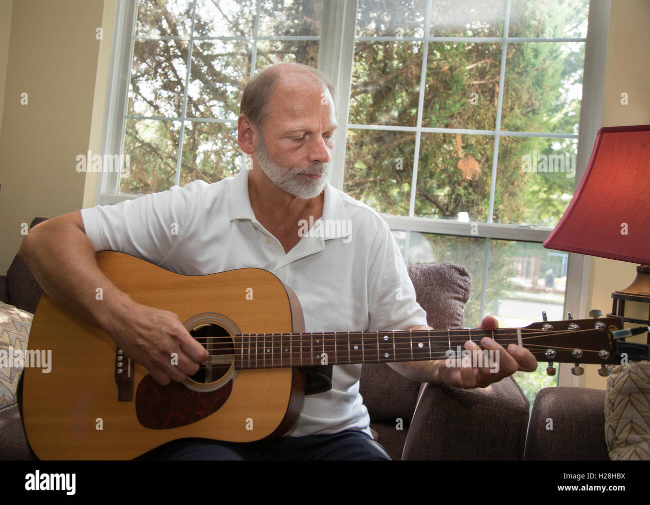 Mann spielt Gitarre in seiner Wohnung Stockfoto