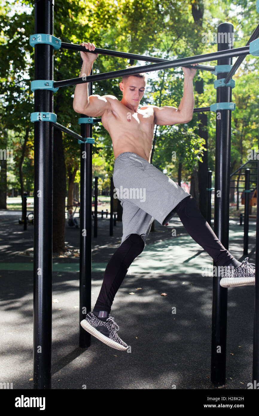 Junger Mann tun Pull Ups auf horizontale Leiste im Freien, Training, sp Stockfoto