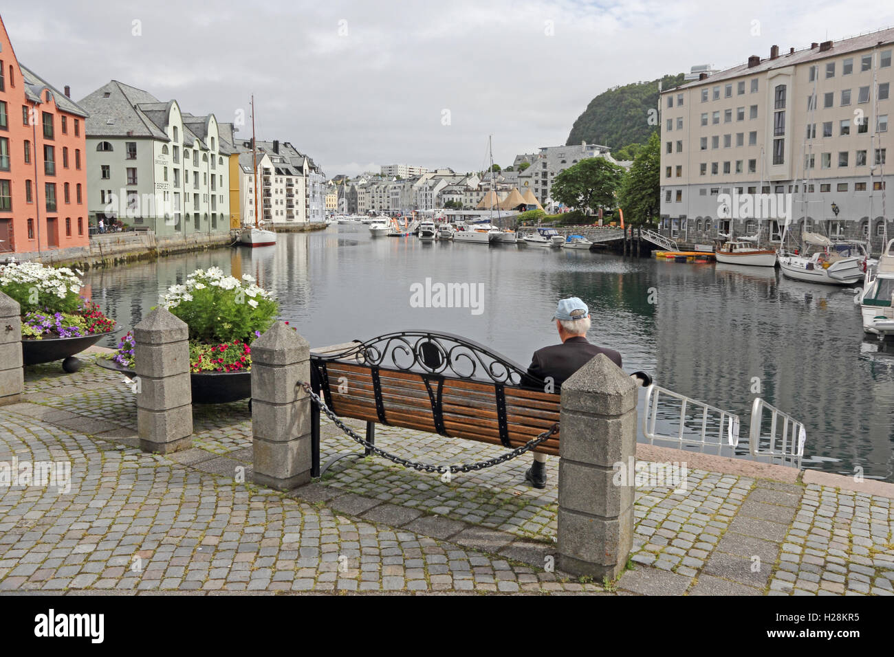 Alter Mann saß auf Bank Suche entlang Inner Harbour, Alesund, Norwegen Stockfoto