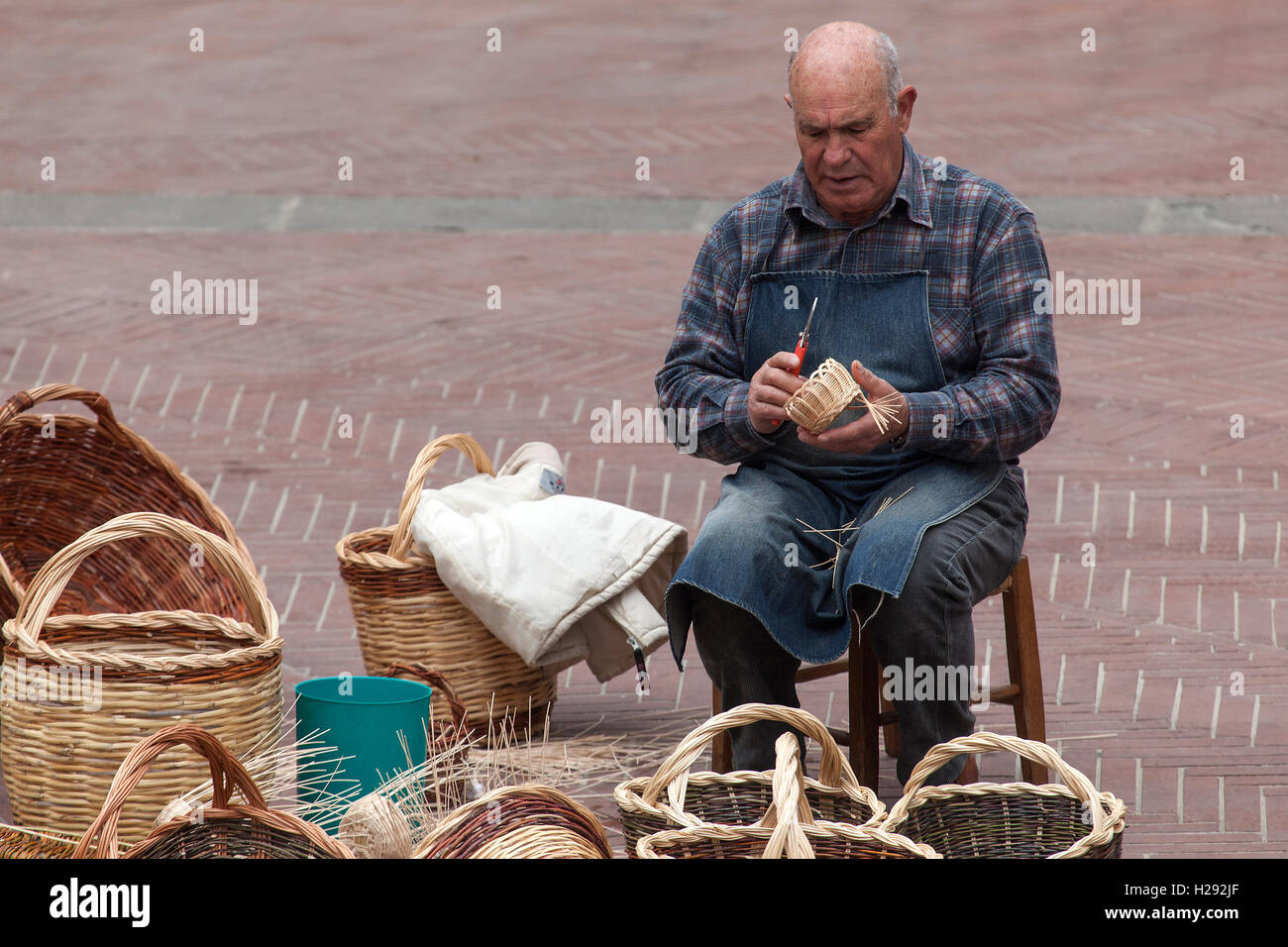 Korbflechter, Menschen auf der Piazza delle Erbe, Körbe, San Gimignano in der Provinz Siena, Toskana, Italien Stockfoto