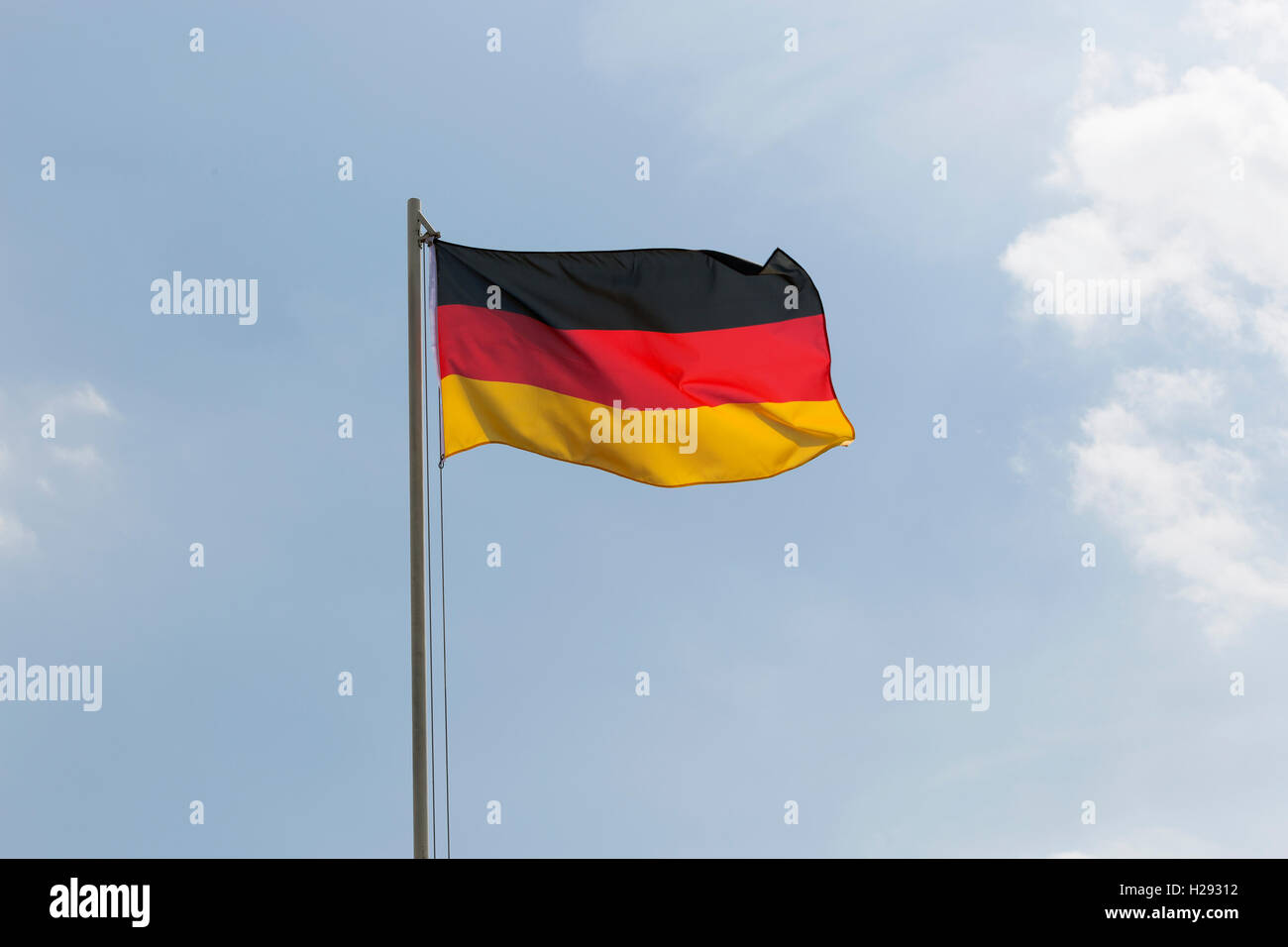 Nationalflagge von Deutschland auf ein Fahnenmast vor blauem Himmel Stockfoto