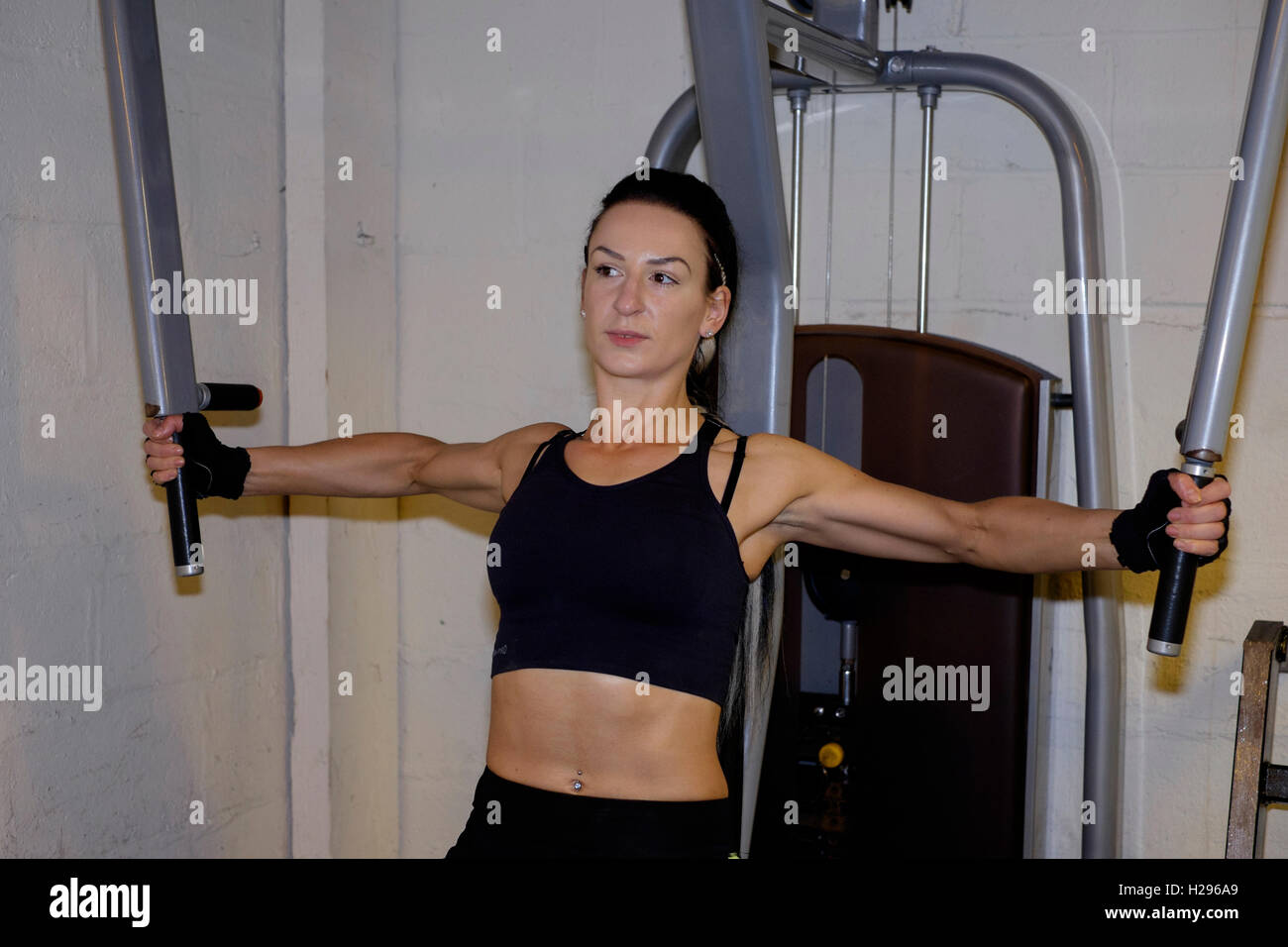 junge Frau mit Arm Ausrüstung zu stärken, während arbeiten in einem Fitness-Studio-England-Vereinigtes Königreich Stockfoto
