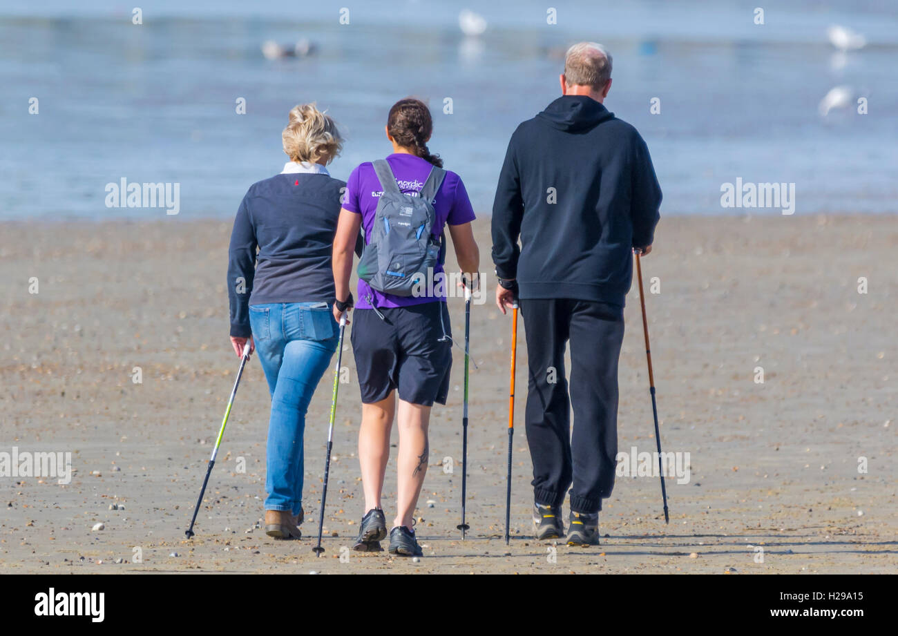 Gruppe von Menschen zu Fuß am Strand mit Stöcken. Stockfoto