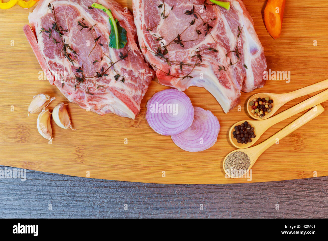 Perfekte rohen Schweinenacken mit Gewürzen, reife Tomaten, roten Zwiebeln und frische Basilikumblätter Closeup auf Holz Schneidebrett. Ansicht von oben Stockfoto
