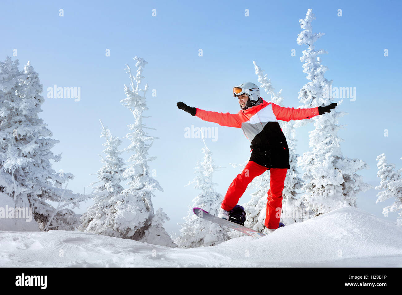 Snowboarder posiert auf blauen Himmel Hintergrund in Bergen Stockfoto