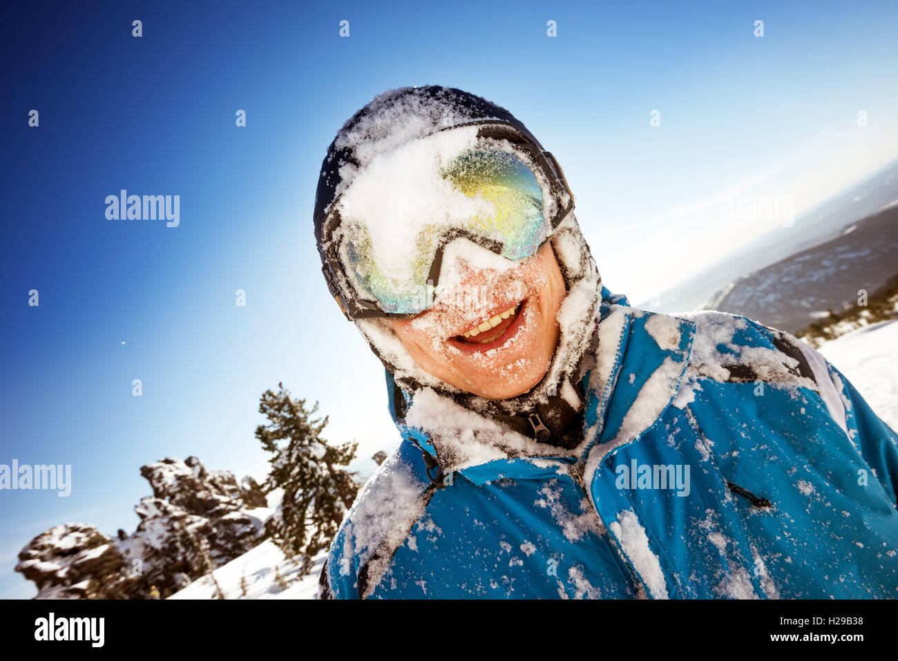 Snowboarder posiert auf blauen Himmel Hintergrund in Bergen Stockfoto