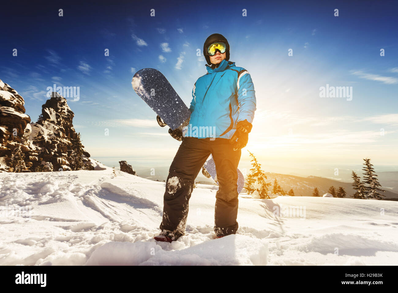 Snowboarder posiert auf blauen Himmel Hintergrund in Bergen Stockfoto