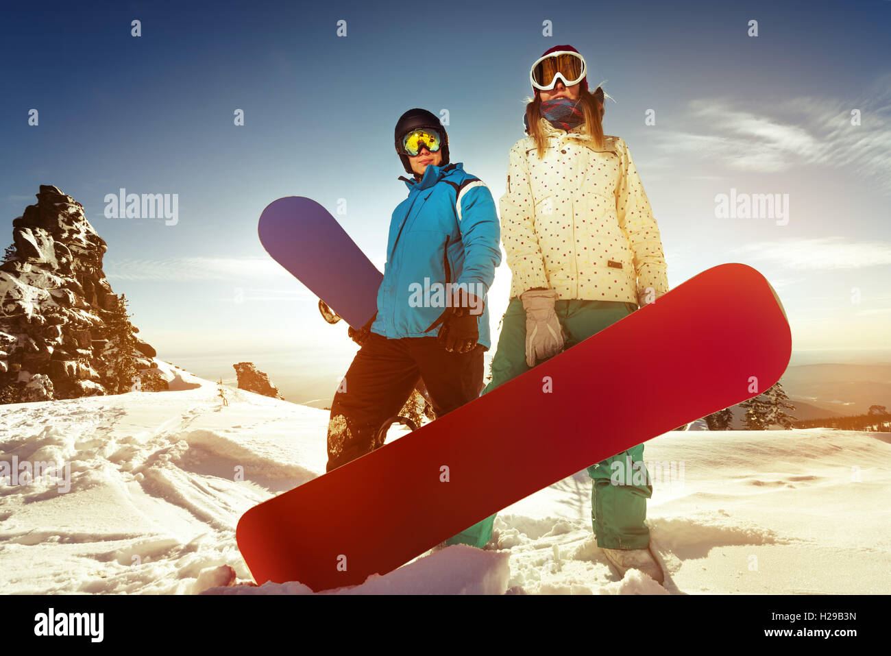 Snowboarder posiert auf blauen Himmel Hintergrund in Bergen Stockfoto