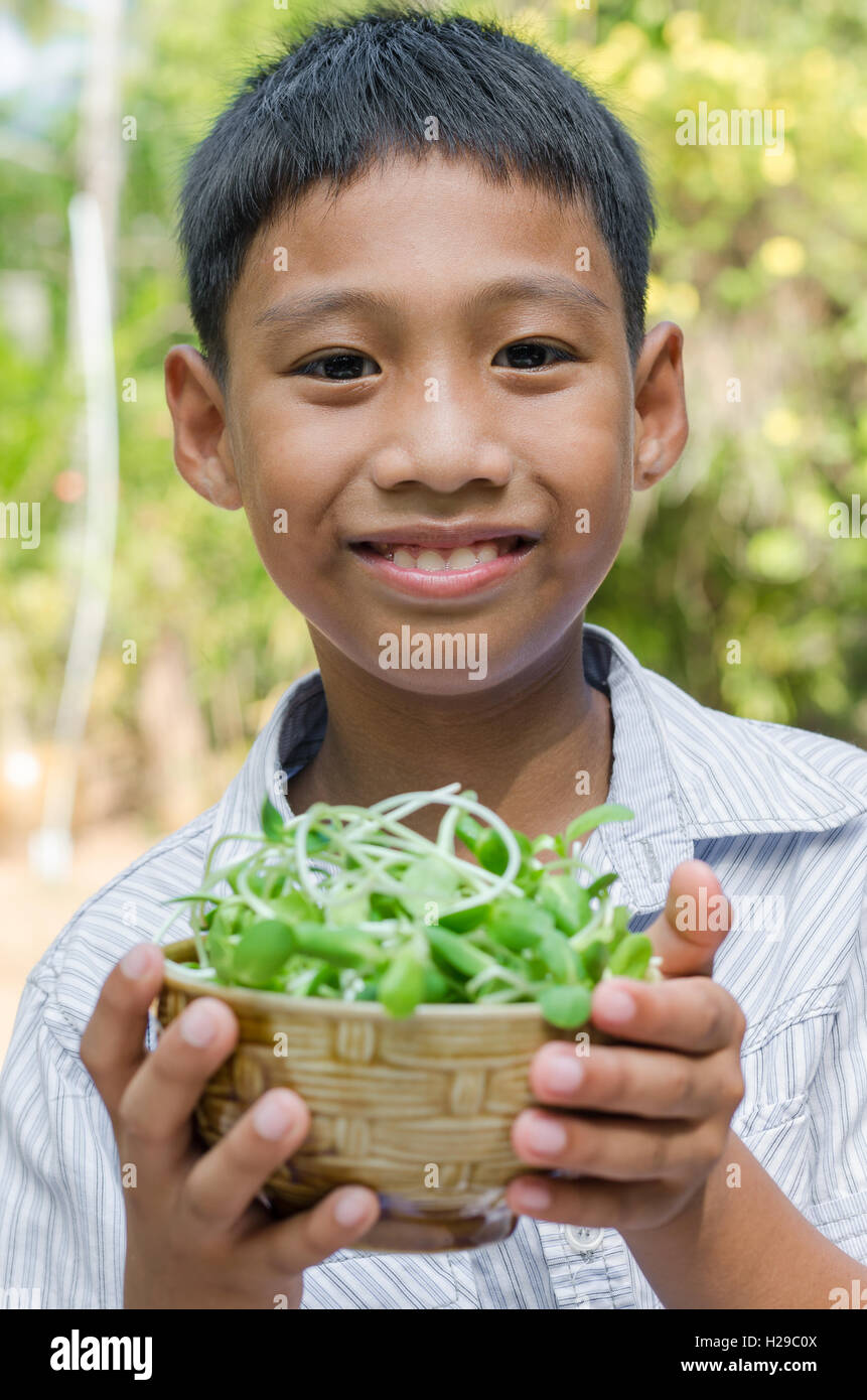 Asiatische Kind genießen, mit Gemüse (Sonnenblumen-Sprossen). Stockfoto